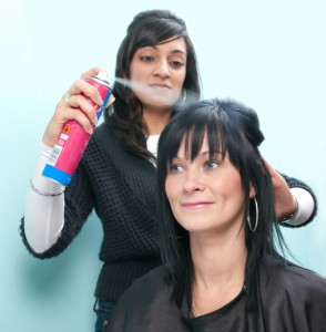 Hair stylist sprays customer's hair